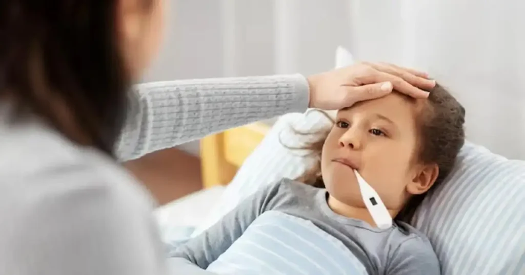 Seorang ibu mengecek suhu tubuh anaknya yang sedang demam menggunakan termometer sebagai langkah awal memahami apa itu KIPI dan cara menanganinya.